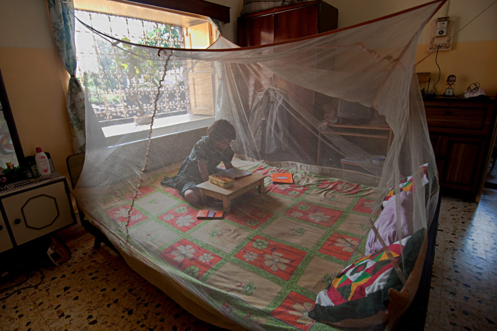 A yoA young girl reading under a malaria bednet. Photo: UNDP